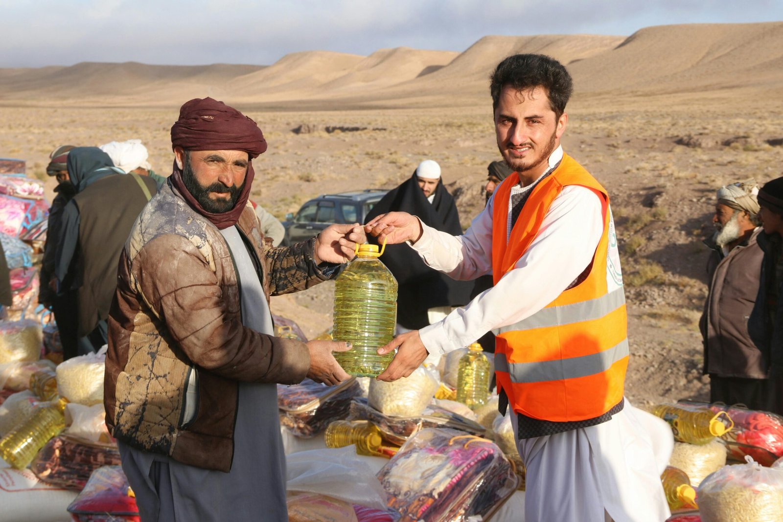 Community members receive supplies during a humanitarian aid distribution in a desert village.